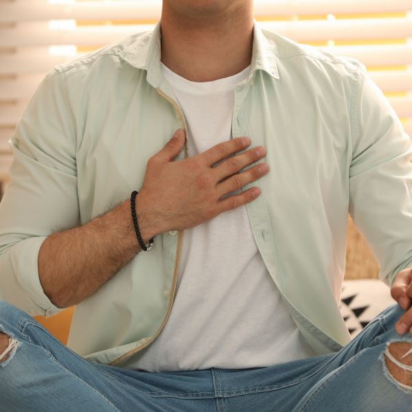 Man sitting cross-legged meditating with his hand on his chest.