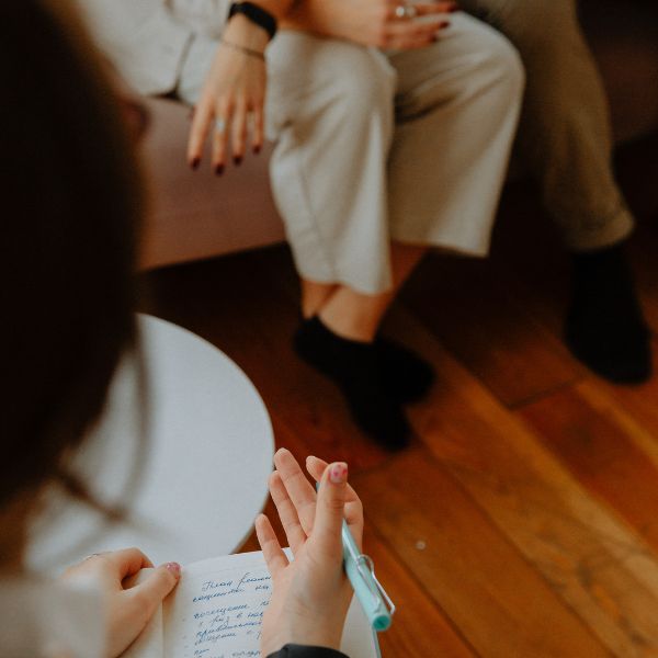 Therapist taking notes during a client session, representing a professional healing consultation.