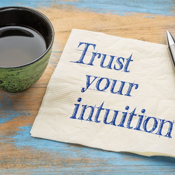A green cup of tea next to a napkin with the words "Trust your intuition" written on it.